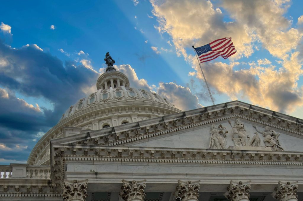 Photo of the U.S. Capitol Building with American flag waving during the daytime